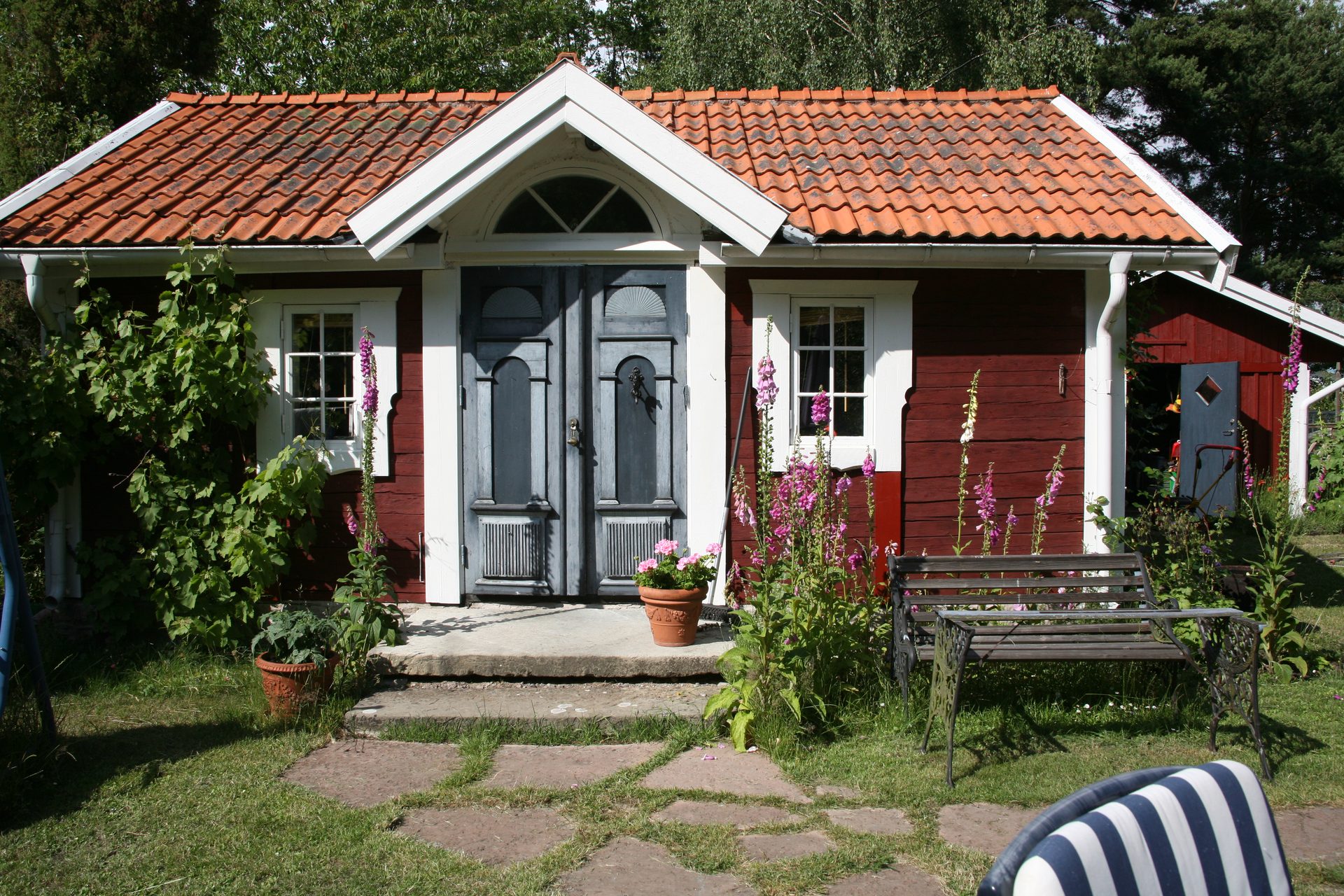The red timber cabin and its garden in summer